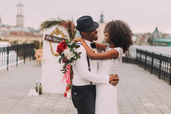 Elegante africano sposo in cappello e la sua bella sposa felicemente ridendo. Giorno del matrimonio — Foto Stock