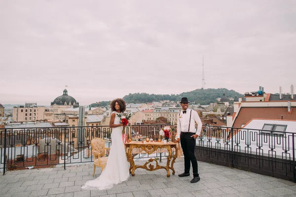 Casal de casamento africano encantador no terraço com vista incrível sobre a arquitetura antiga Lviv — Fotografia de Stock