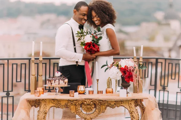 Charmantes schwarzes Hochzeitspaar hält Händchen auf der Terrasse — Stockfoto