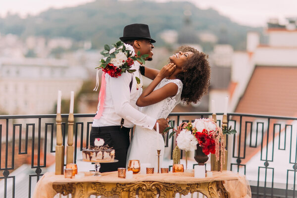Elegante coppia di sposi africani che si diverte sul balcone con tavolo dorato di lusso in stile orientale in primo piano — Foto Stock