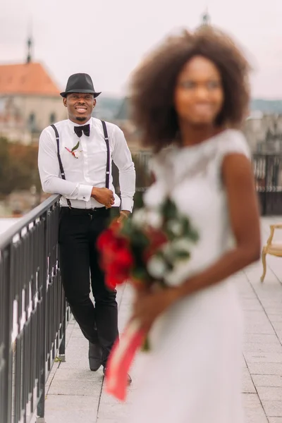 Elegante novio negro en foco y su encantadora novia en la azotea. Ceremonia de boda — Foto de Stock