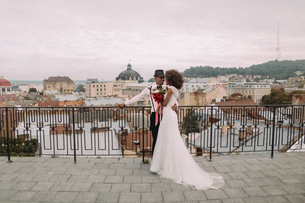 Happy black wedding couple softly hugging on the rooftop