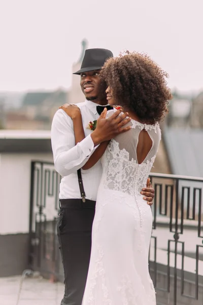 Belos recém-casados negros suavemente abraçando no telhado — Fotografia de Stock