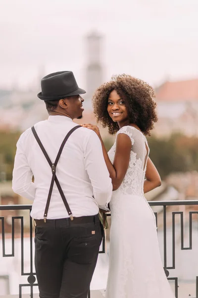 Güzel Afrikalı gelin ve şık damat şapka çatıda el ele tutuşarak