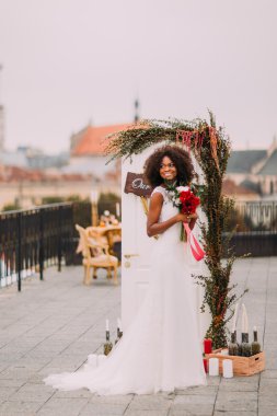 Çiçekler ve düğün malzeme ile dekore edilmiş teras poz beyaz vintage dantel elbise içinde zarif Afrika gelin