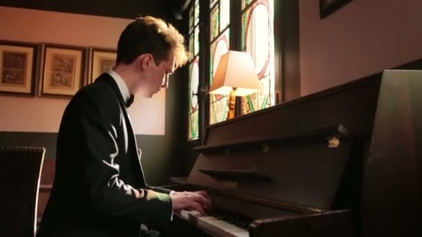 ハンサムな新郎は、暗い部屋でピアノを弾きます。ロマンチックなパリの新婚旅行. — ストック動画
