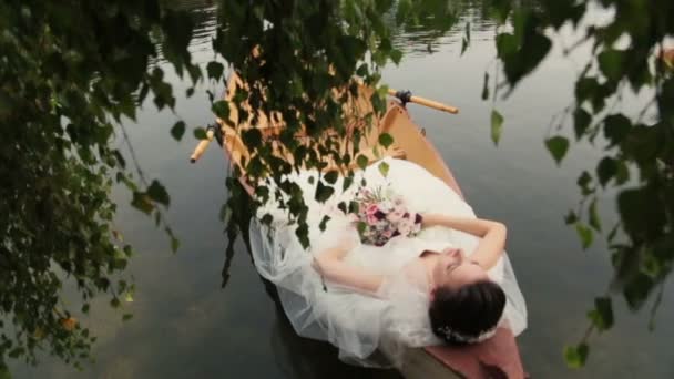 Okouzlující brunetka nevěsta, ležící v kánoi s kyticí v ruce. Líbánky v Paříž, Francie.