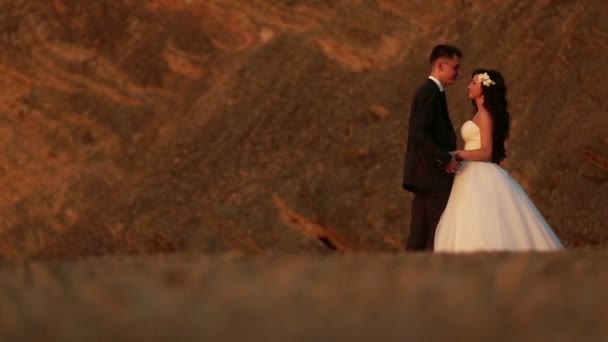 Mooie brunette bruid en knappe bruidegom kussen in de bergen — Stockvideo
