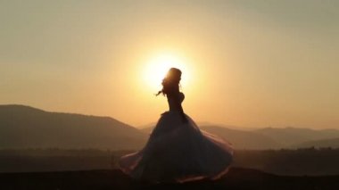 Sevimli gelin incelikle dağlarda günbatımı üzerinde dans silüeti