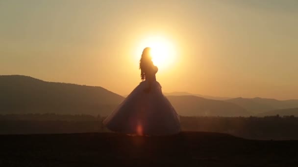 Силуэт красивой невесты, танцующей на закате в альпийских горах — стоковое видео