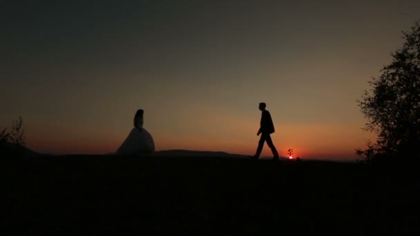 Pareja de boda se reúne en la cima de la colina en las montañas al atardecer — Vídeo de stock