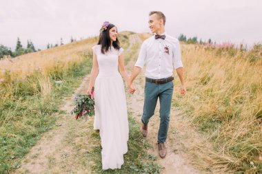 Güzel düğün çifti eller ve yürüyüşlere yolda n dağlar tutun