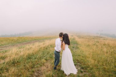 Mutlu evlilik çift tutan eller ve mesafe içine bak. Puslu dağlar arka plan