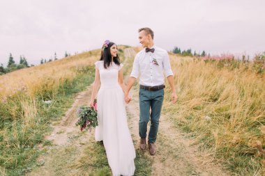 Çift düğün dağlarda yolda yürür. Balayı