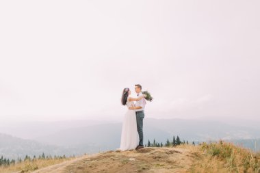 Gelin ve damat usulca dağın zirvesinde sarıl. Dağlarda balayı