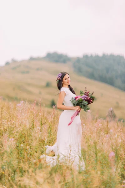 Bella sposa in piedi con bouquet sul campo in montagna Alpian — Foto Stock