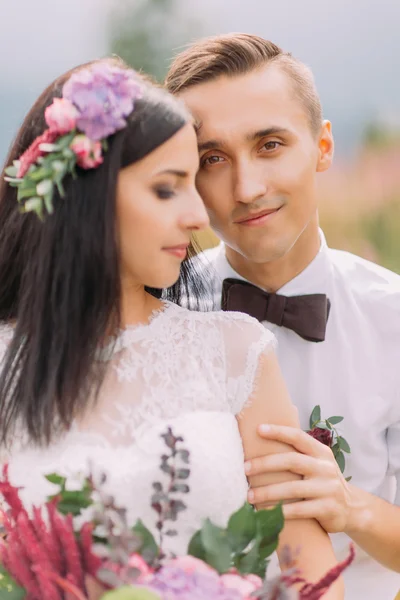 Retrato de belo casal de casamento com flores em mãos de perto — Fotografia de Stock