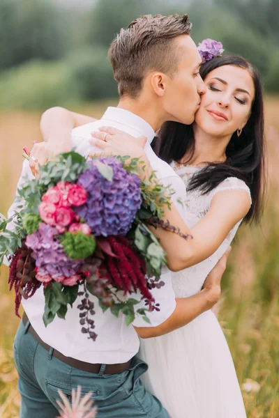 Knappe bruidegom kussen mooie bruid. Bergen op achtergrond — Stockfoto