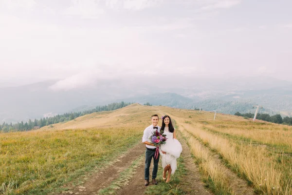 Matrimonio coppia in posa sul sentiero tra le montagne nebbiose — Foto Stock