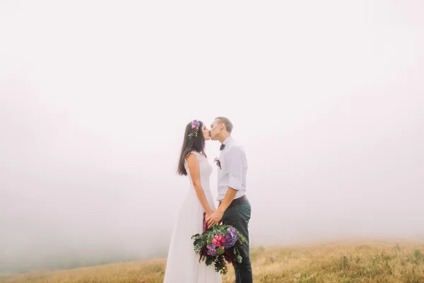 新婚夫妇吻在球场上。雾背景 — 图库照片