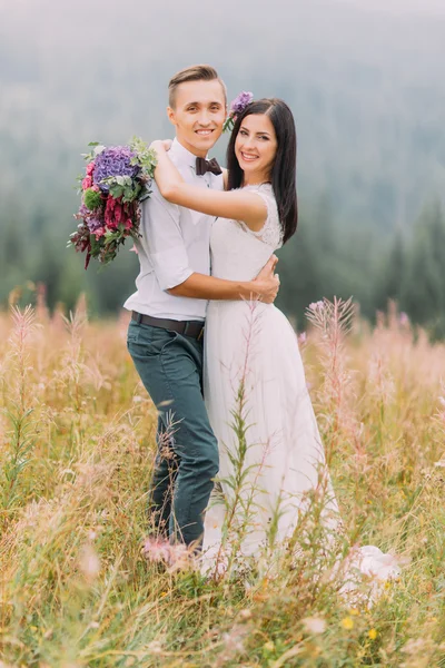 Mutlu gelin ve damat kamera için poz. Arka planda dağlar