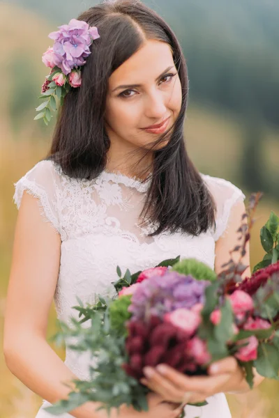 Retrato de hermosa novia morena con ramo en las manos. Luna de miel en las montañas alpinas — Foto de Stock