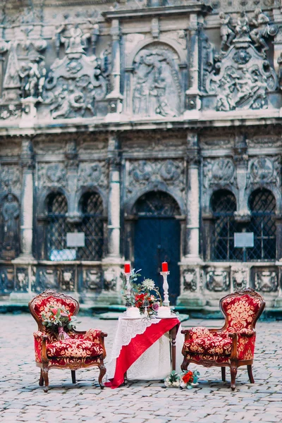 Мрійливий червоно-білий кольоровий стіл з розкішними кріслами зі старою архітектурою бароко на фоні — стокове фото