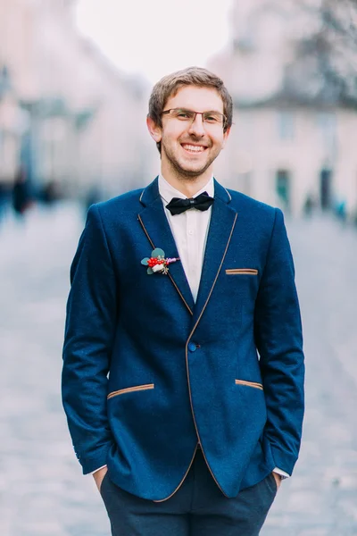 Beau marié posant en costume bleu avec une vieille architecture Lviv sur fond — Photo