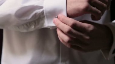 Damat şık kol düğmeleri takar. Yakın çekim.
