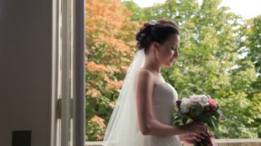 Güzel esmer gelin düğün buket pencerenin duran ile