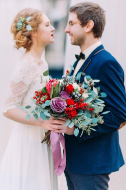 Genç güzel gelin düğün buketi ve şık damat sevgiyle birbirine bakarak