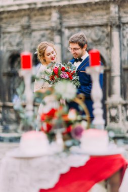 Sevimli sarışın gelin ve yakışıklı damat iki ön plan onların düğün töreni ile ustaca süslü masa zevk