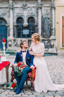 Yakışıklı damat ve gelin şefkatle birbirlerine bak. Arka plan güzel eski Lviv mimarisinde.