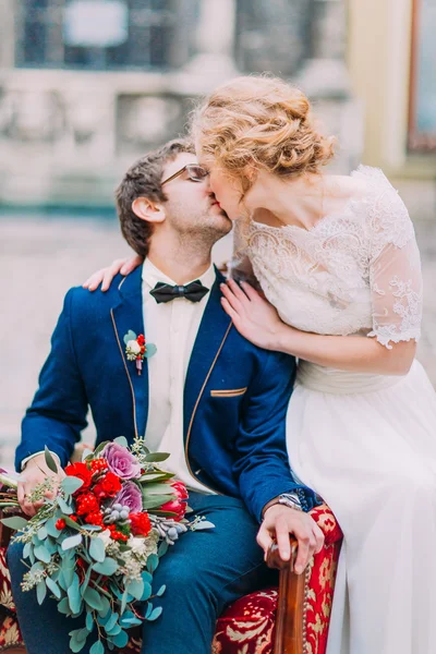 Noiva e noivo beijando e sentado em cadeiras vermelhas — Fotografia de Stock