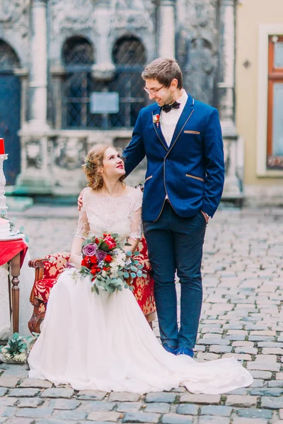 El novio guapo y la novia se miran con ternura y amor. Increíble arquitectura antigua de Lviv en el fondo — Foto de Stock
