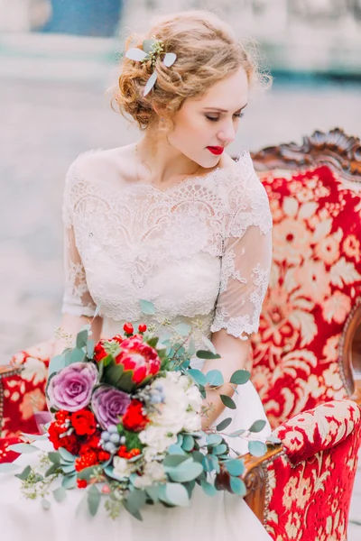 Novia aristocrática con el pelo rubio rizado se sienta en el sillón vintage y disfrutar del momento — Foto de Stock