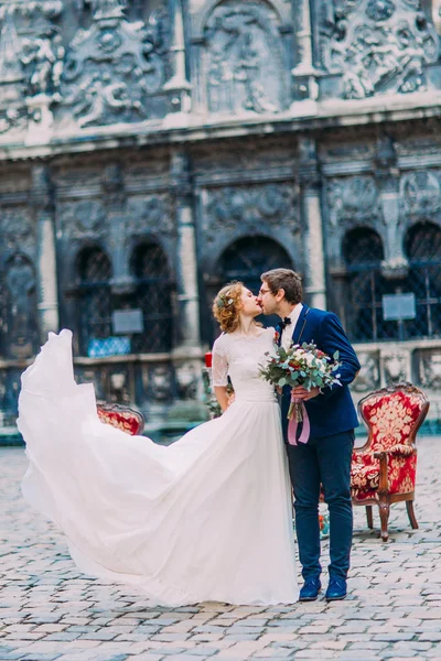 Pohledný ženich líbá nevěstu krásnou blond s starého Lvova architektura na pozadí — Stock fotografie