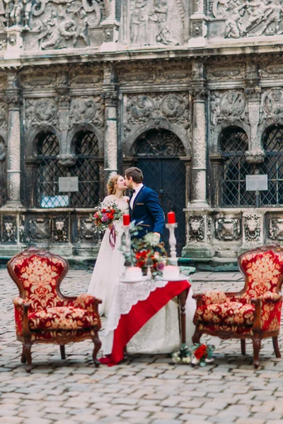 Casamento casal suavemente beijando perto da mesa de luxo para dois setted para eles — Fotografia de Stock