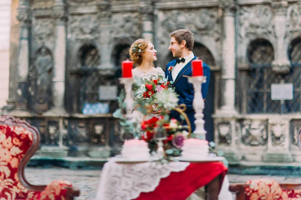 Recién casados se miran amorosamente con la vendimia decorada con flores en primer plano — Foto de Stock