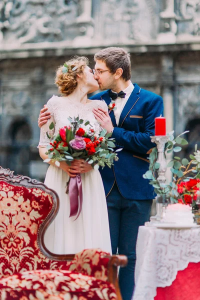 Casal de casamento incrível beijando com o vintage decorado com mesa de flores em primeiro plano — Fotografia de Stock
