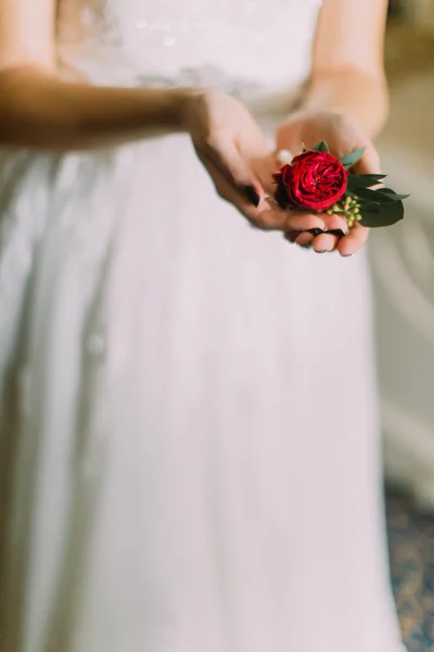 Bride in white lace dress holding boutonniere of red rose close up — Stock Photo, Image