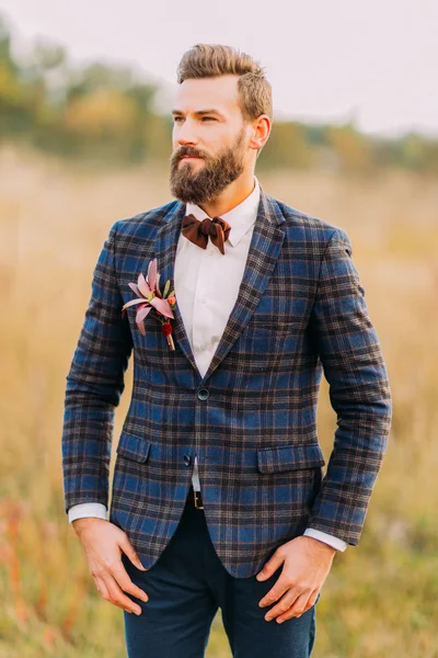 Handsome bearded groom in jacket posing on the autumn field — Stock Photo, Image