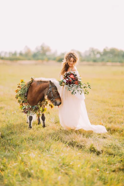 Bella sposa con piccolo pony nel campo — Foto Stock