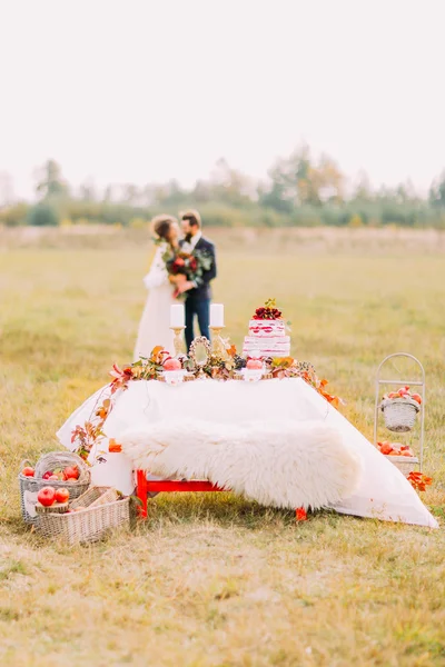 Bruidspaar zoenen op veld met vakantie tabel als voorgrond — Stockfoto