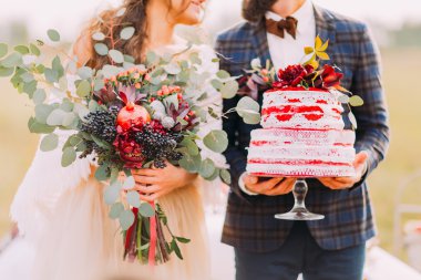 Wedding couple holds beautiful cake and bouquet close up clipart