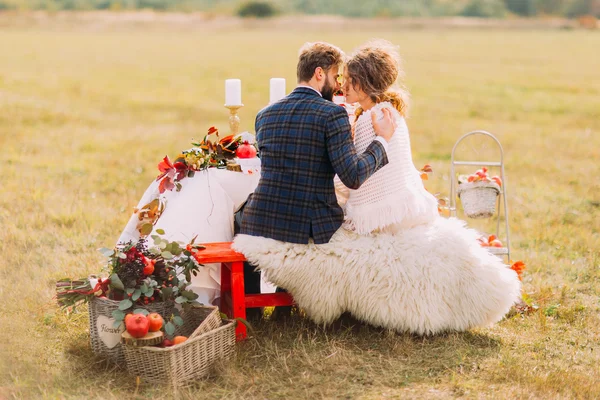 Casamento casal beijos na mesa de férias no campo. Visão traseira — Fotografia de Stock