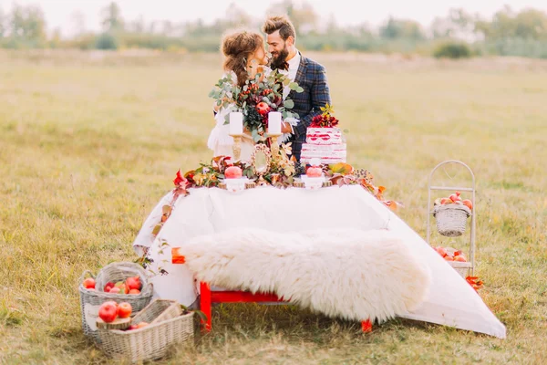 Šťastný Svatební pár sedící u stolu dovolená v poli — Stock fotografie