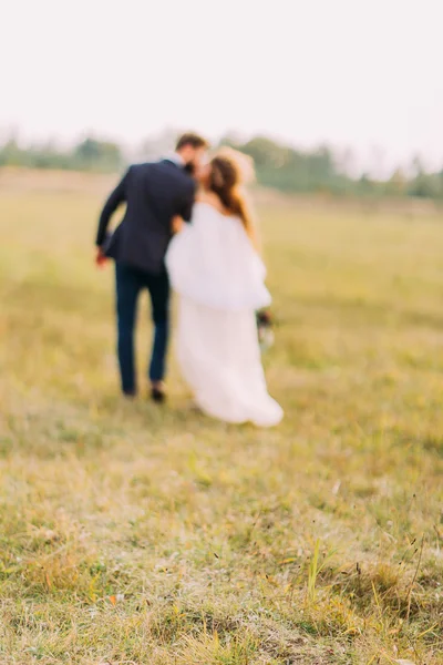 Glückliche Braut und Bräutigam küssen sich auf dem Feld auf dem Land — Stockfoto