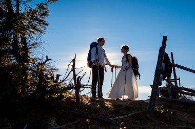 Beautiful tourist wedding couple standing against the sun. Alpine mountains background