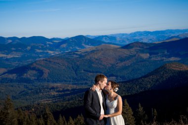 Bride and groom softly kissing. Amazing mountains view on background